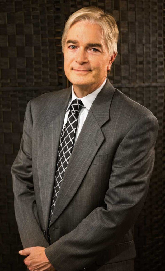 man with gray hair wearing dark suit and black and silver tie with crosshatch pattern