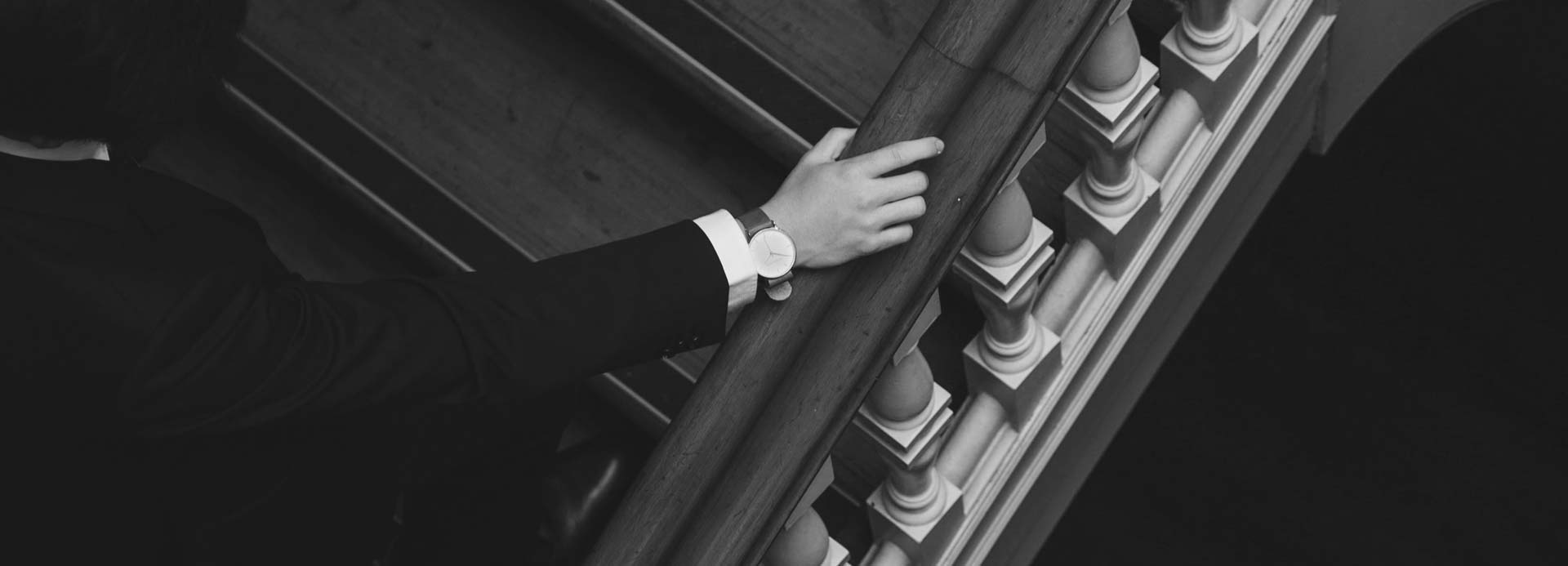 overhead view of man in suit with watch walking up staircase with hand on railing